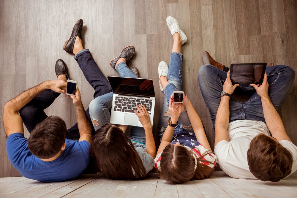 Group of young people sitting on the floor using a laptop computer, Tablet PC, smart phones