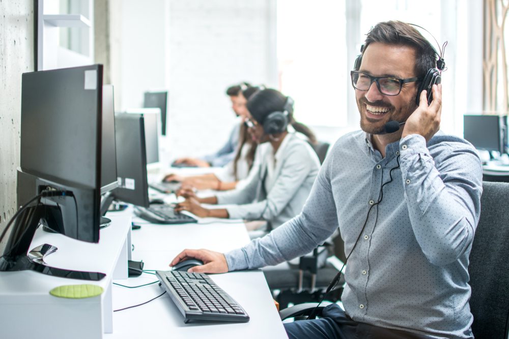Smiling customer support operator with headset working in call centre