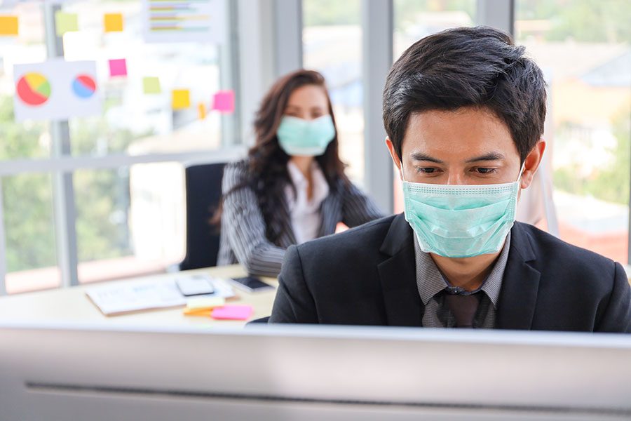 Two bankers wearing face masks after returning to the office