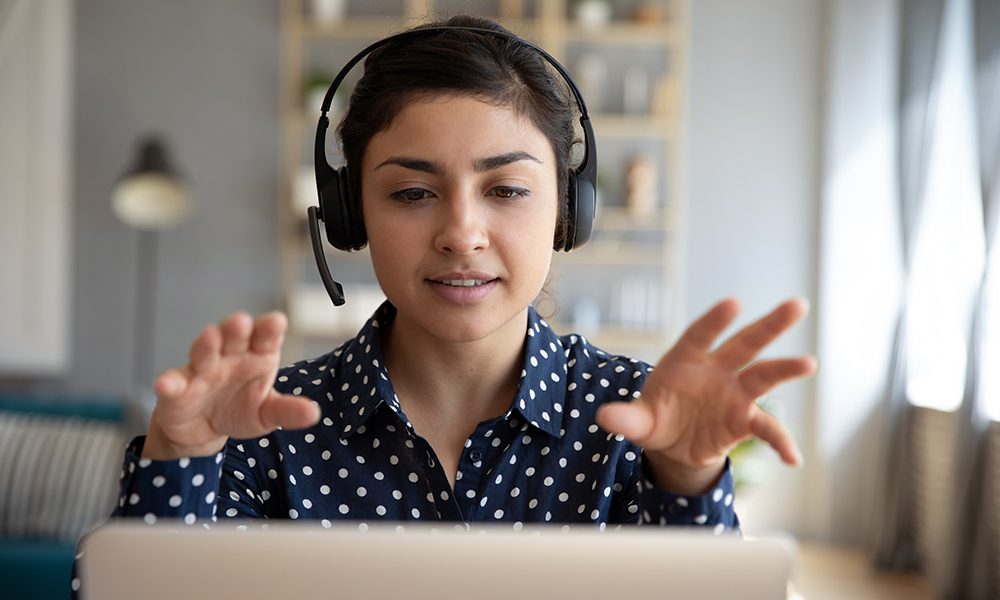 Young businesswoman sat at laptop, working from home, wearing a headset